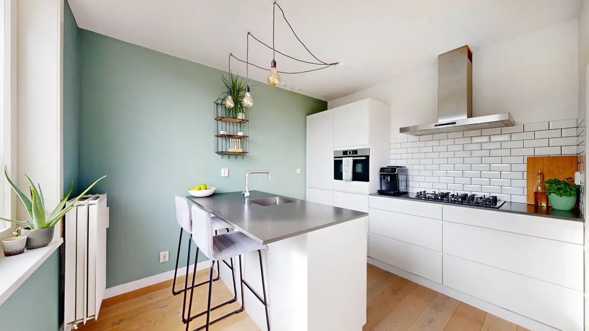 Lichte keuken met kookeiland en groene muur in een Amsterdams appartement