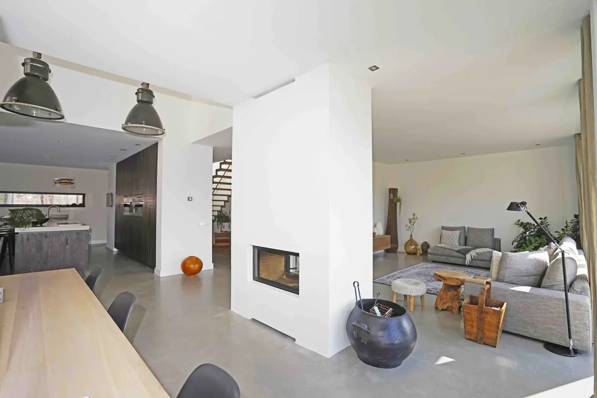 Spacious living room with a fireplace, a long dining table and a staircase