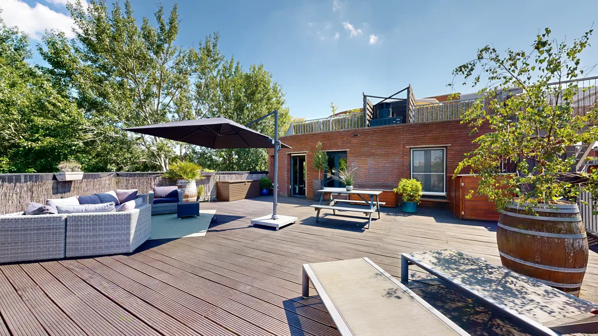 Spacious roof terrace with a lounge sofa and plants in Amsterdam