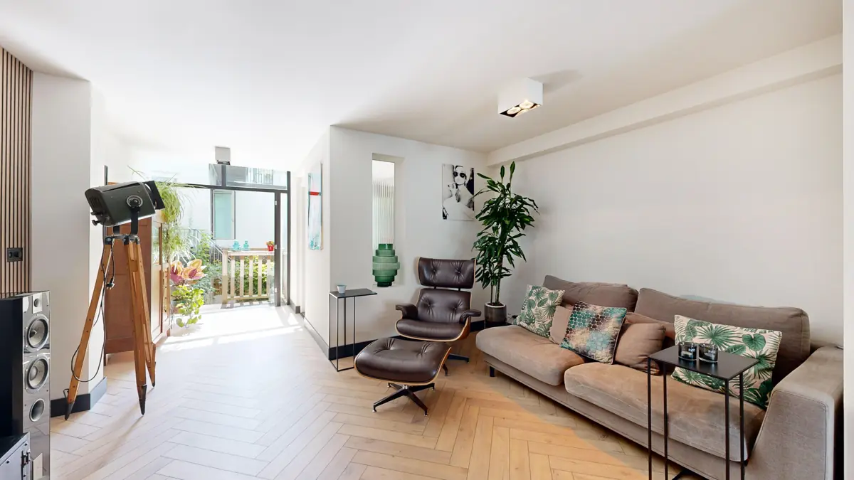 Lichte woonkamer met een bank, een leren fauteuil en tuindeuren