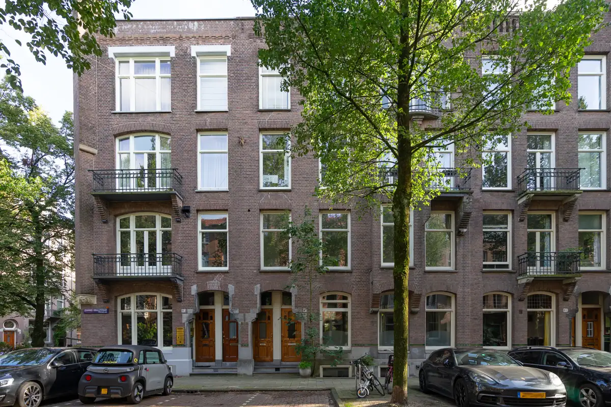 Amsterdamse gevels met balkons en bomen langs de straat