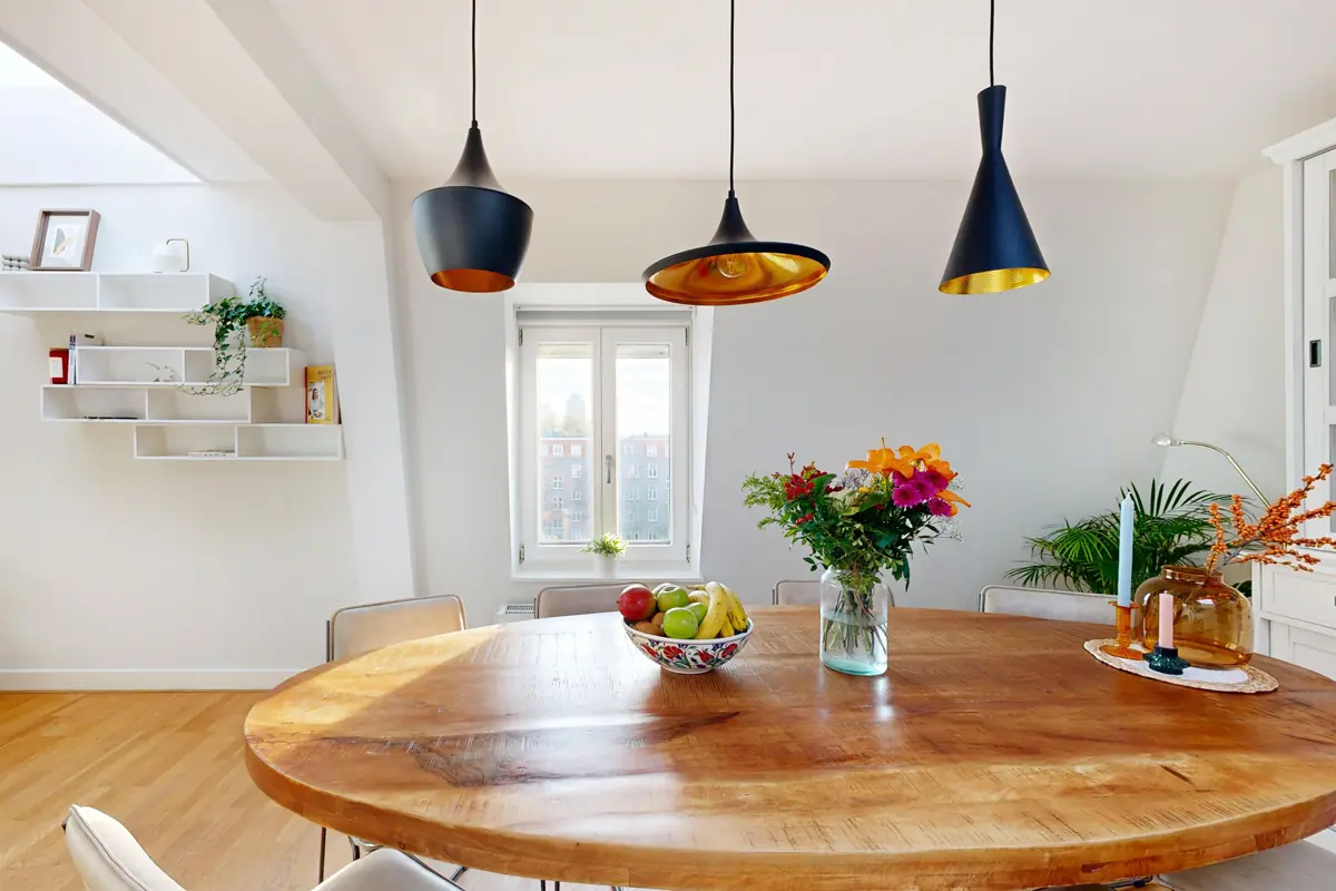 Ronde houten eettafel met bloemen in een lichte woonkamer