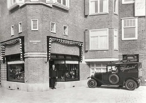 Zwart-witfoto uit 1928 van de hoekwinkel van B.J. de Logie in de Beethovenstraat, met een man voor de etalage en een bestelauto van de wijnhandel