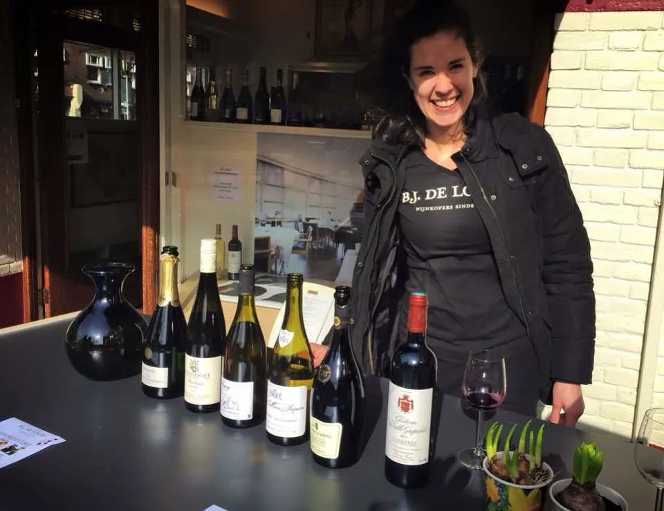Suzanne van Broekhuizen achter een tafel met wijnflessen bij een proeverij voor de winkel aan de Beethovenstraat