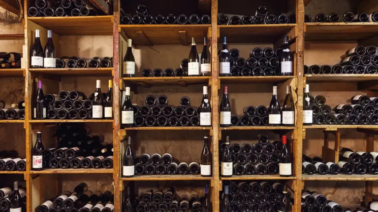 Houten schappen vol wijnflessen in de kelder van wijnhandel B.J. de Logie