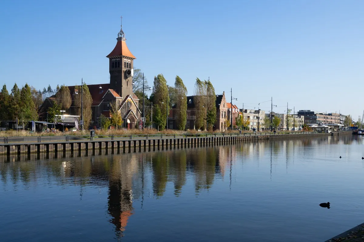 Church with a tower by the water in Diemen, with the trees reflected in the water