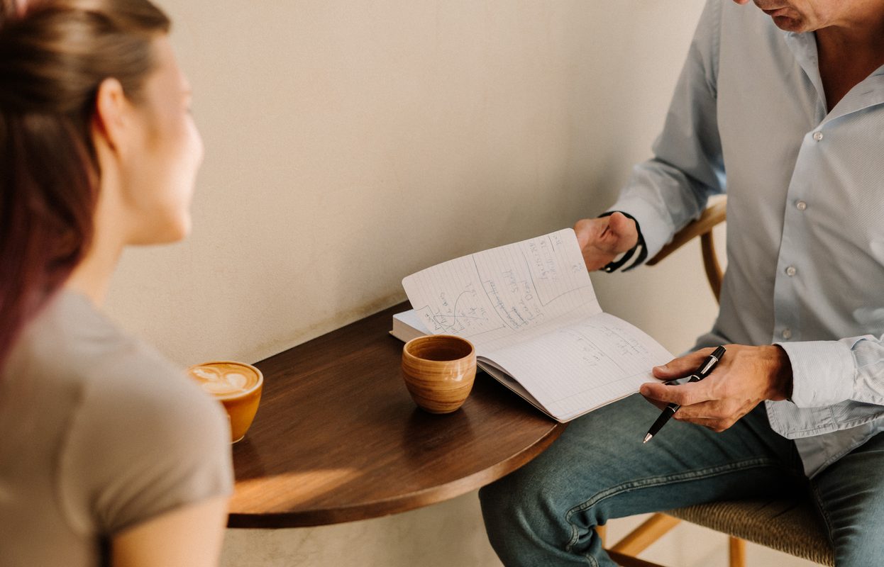 Kennismakingsgesprek aan tafel met koffie en een open notitieboek