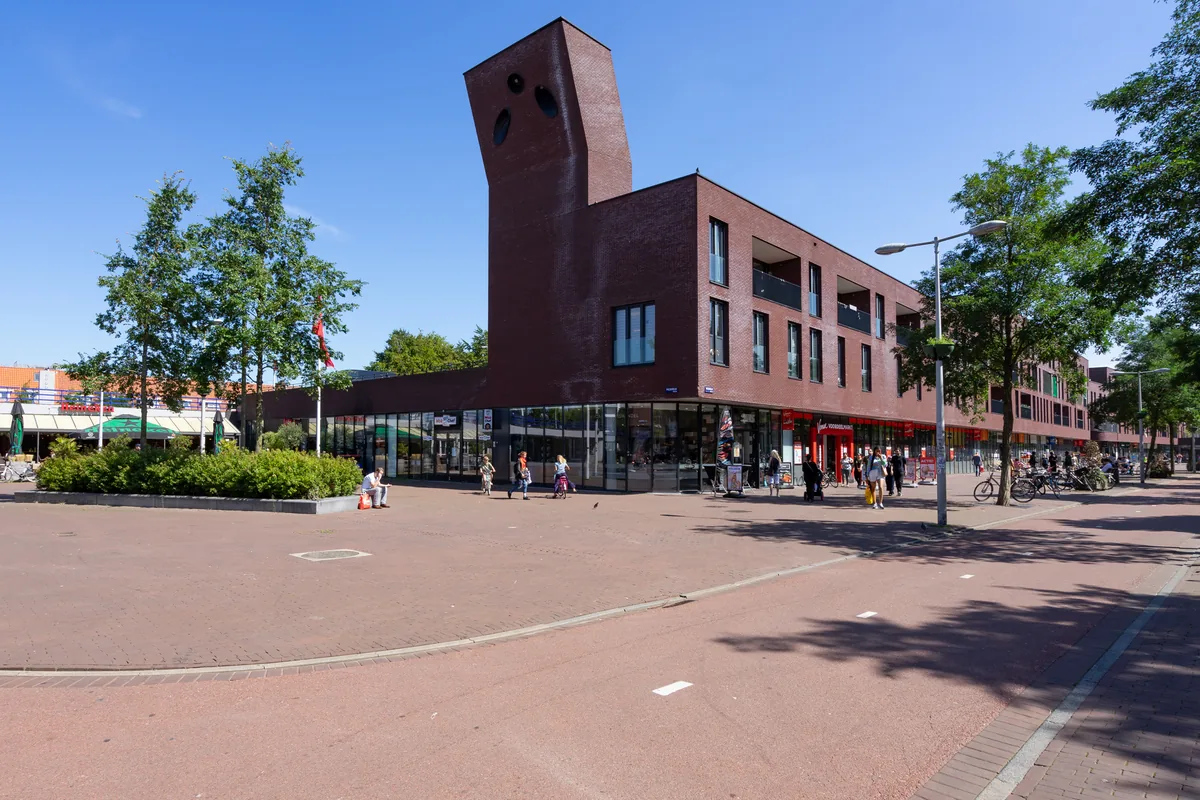 Het Mosplein in Amsterdam-Noord met de bakstenen toren en winkels op de begane grond