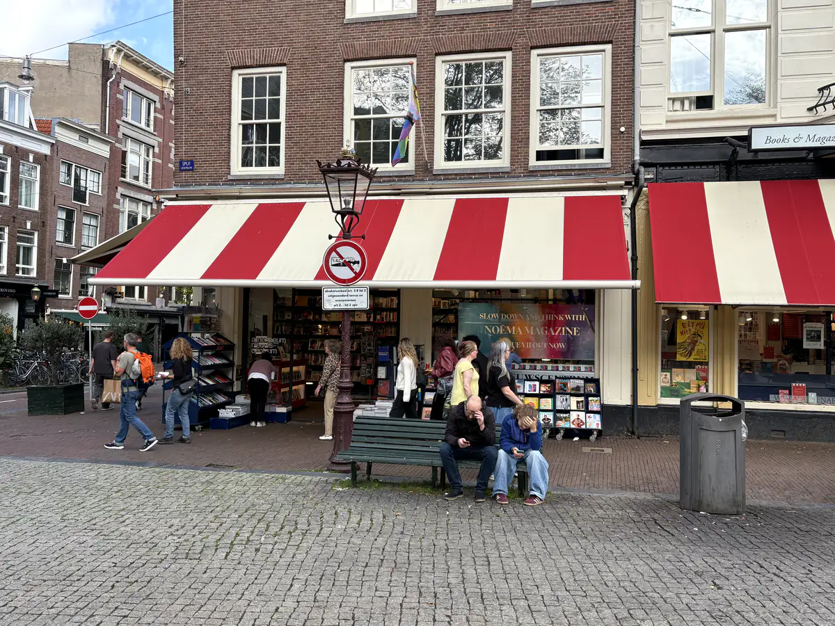 Athenaeum Nieuwscentrum aan het Spui met rood-wit gestreepte luifel en rekken met boeken en tijdschriften voor de deur