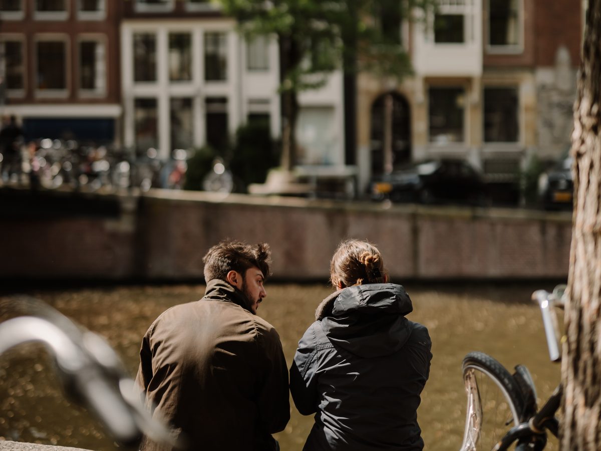 Twee mensen op de kade kijken naar de grachtenpanden aan de overkant