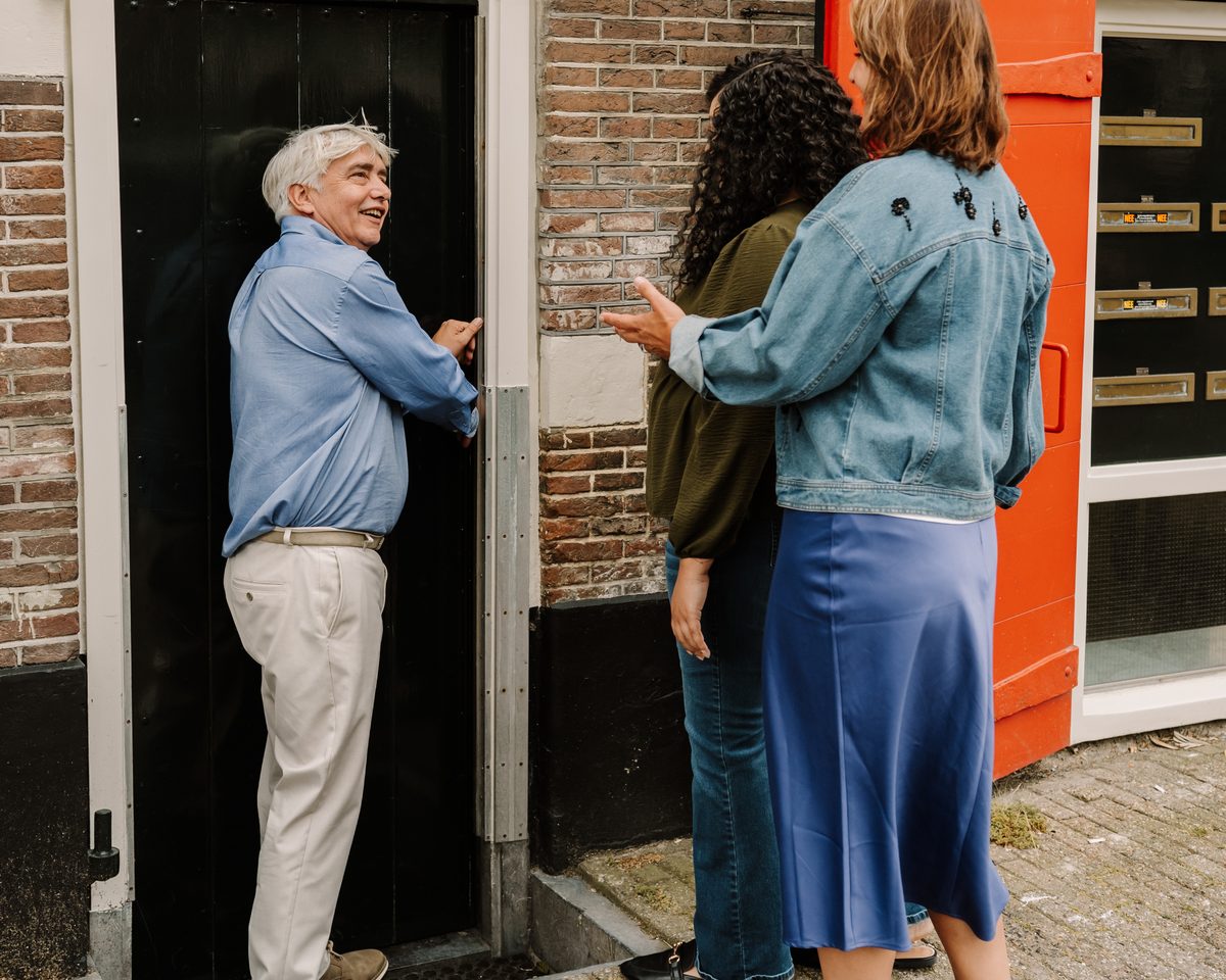 Erik doet de voordeur open voor twee kopers bij een bezichtiging
