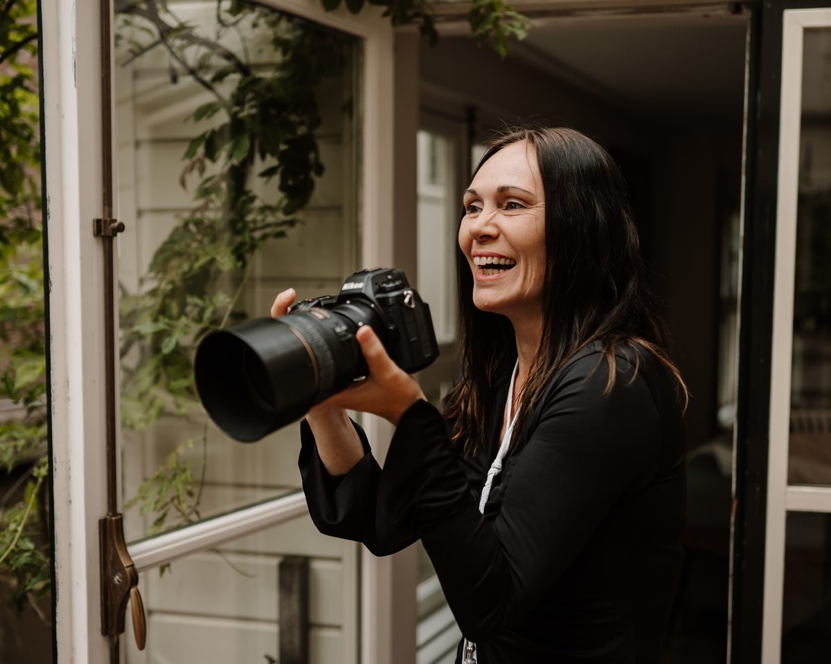 Hadewij, de eigen fotograaf van Makelaar in Amsterdam, met haar camera in een deuropening