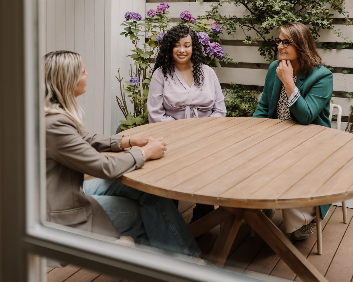 Lisa van Makelaar in Amsterdam in gesprek met twee klanten aan een tuintafel