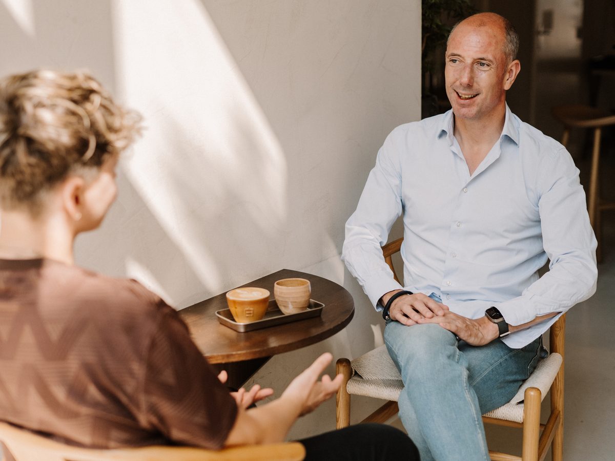 Micha van Makelaar in Amsterdam in gesprek aan tafel met koffie