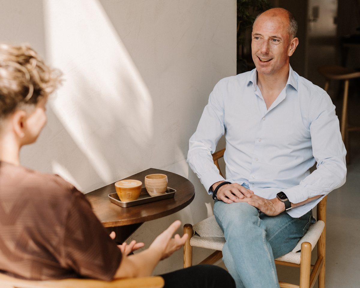 Micha van den Bergh in gesprek aan een tafeltje met koffie