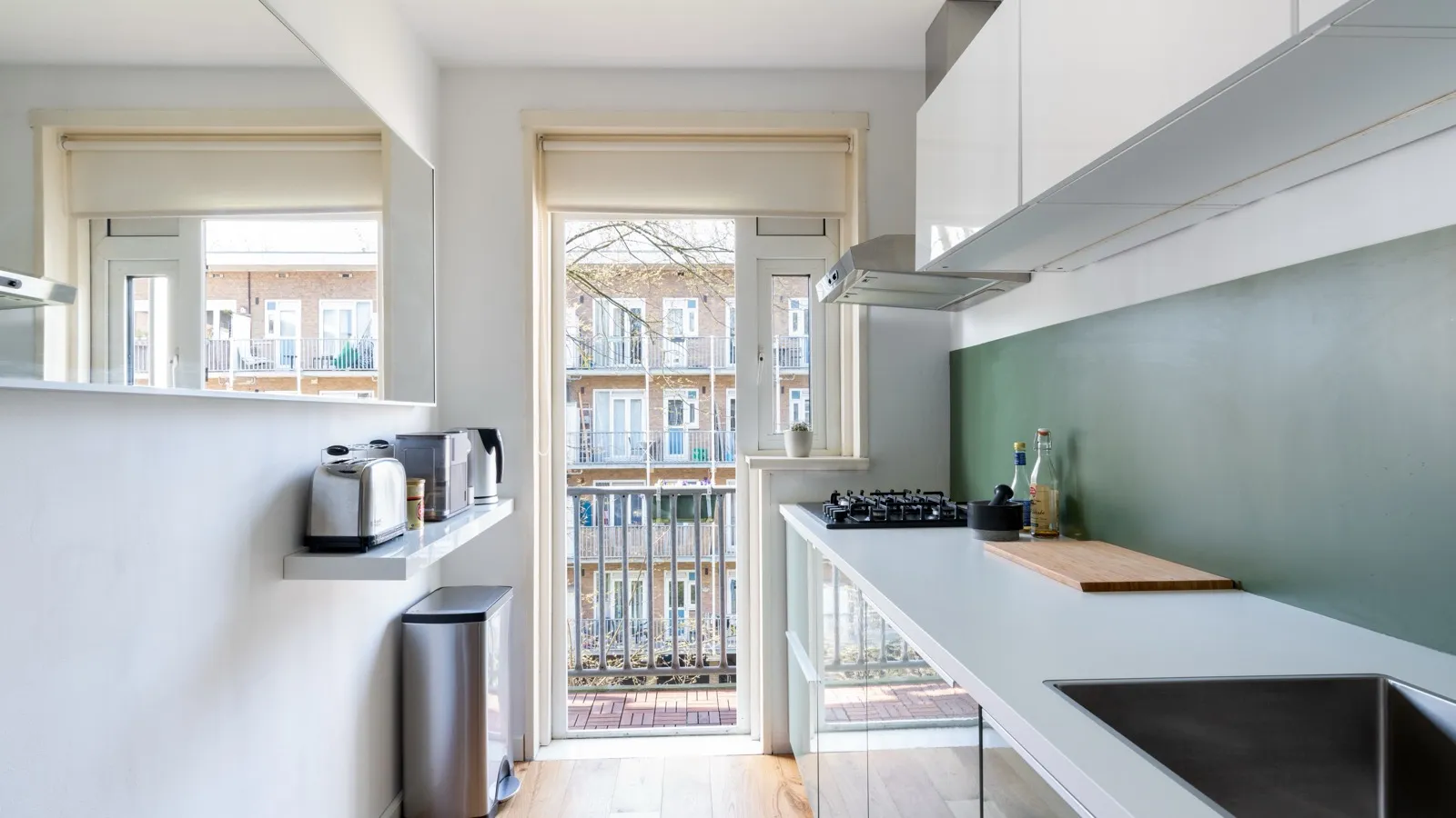 Lichte, verbouwde keuken in een Amsterdams appartement met houten vloer en balkondeur