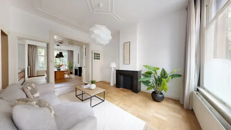 Woonkamer en suite in een Amsterdamse woning met hoge ramen, een radiator onder het raam en een zwarte schouw